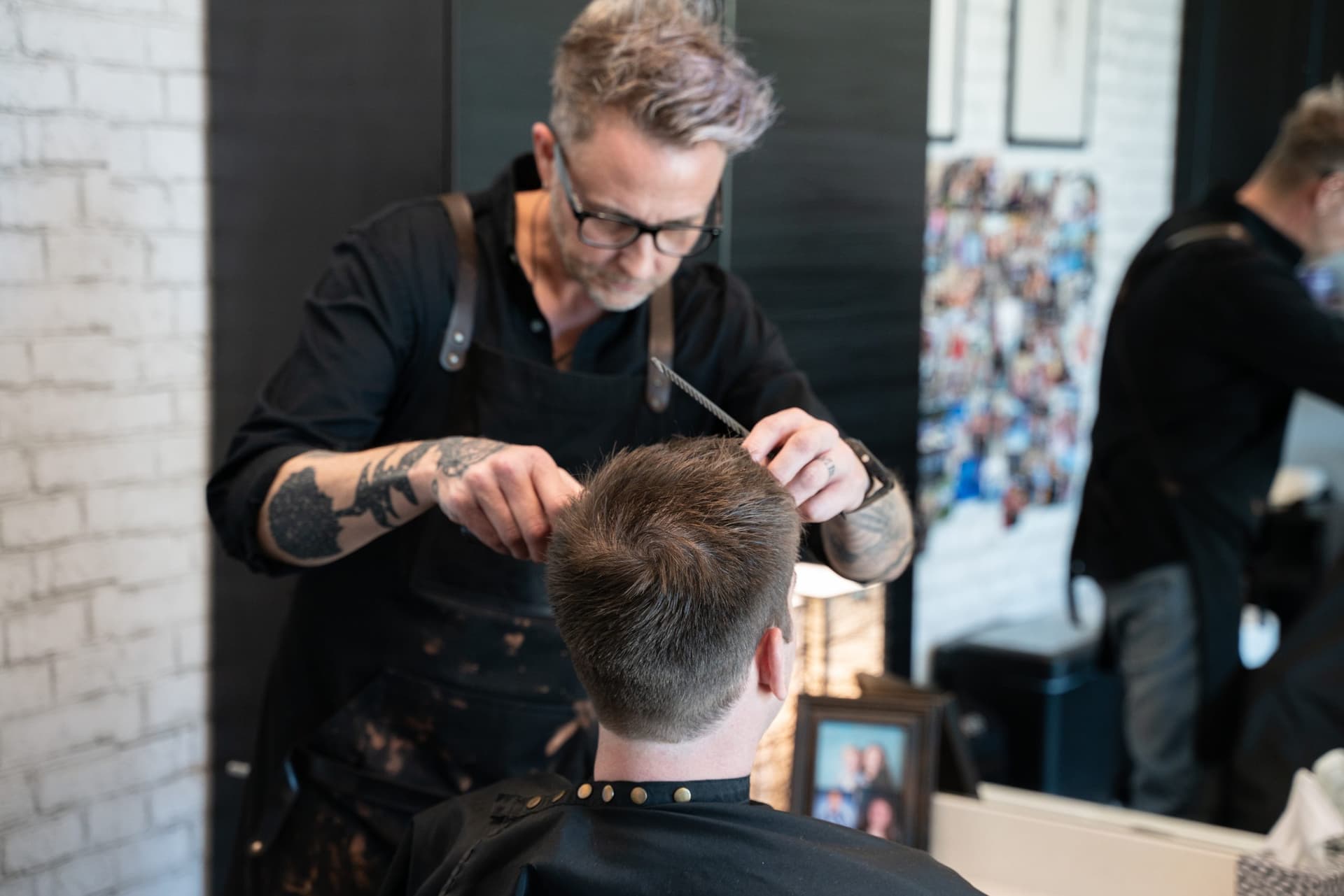 Barber cutting a client's hair in his salon suite