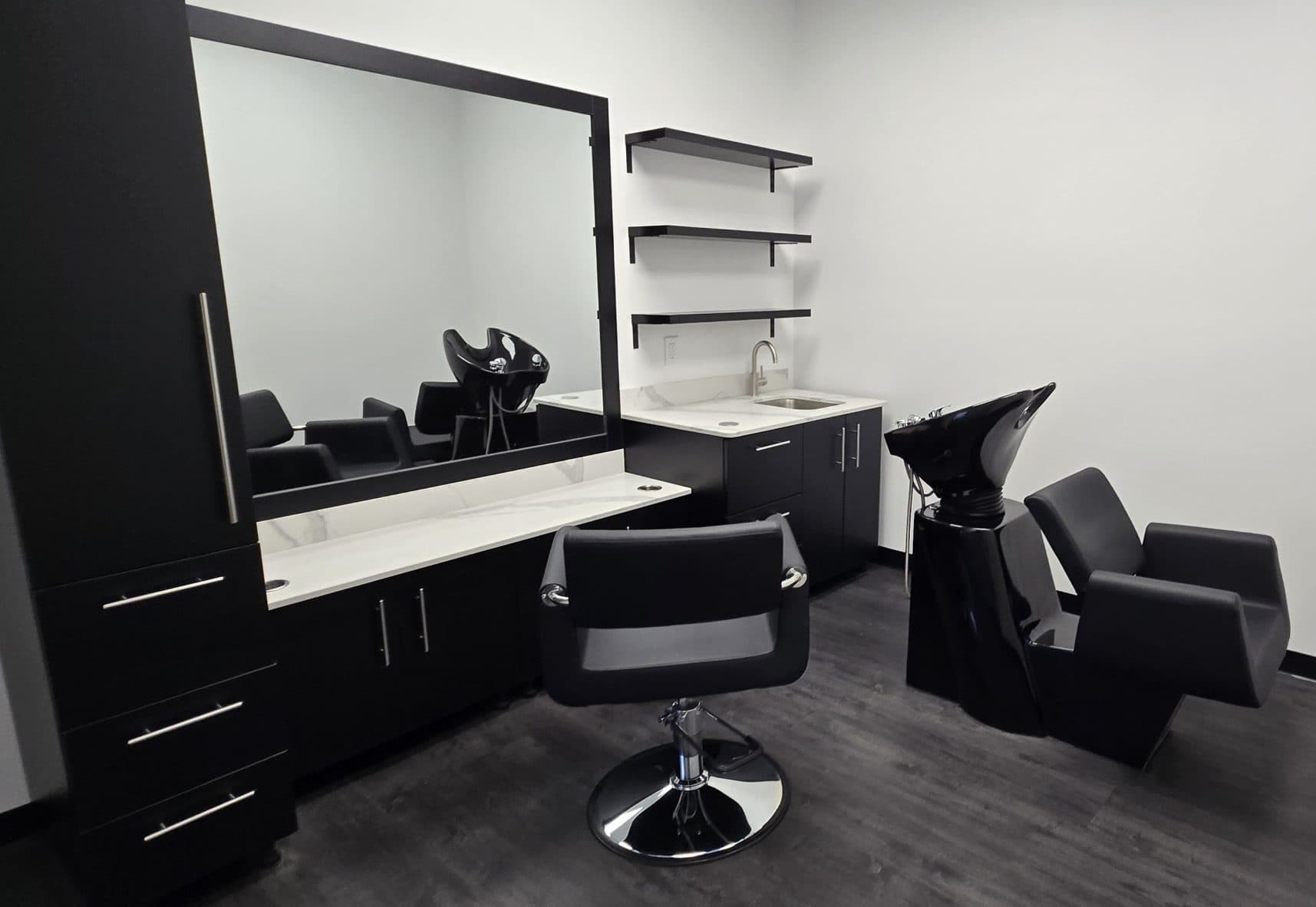 Styling station with large mirror and shampoo bowl in a Florence salon suite at The Hive