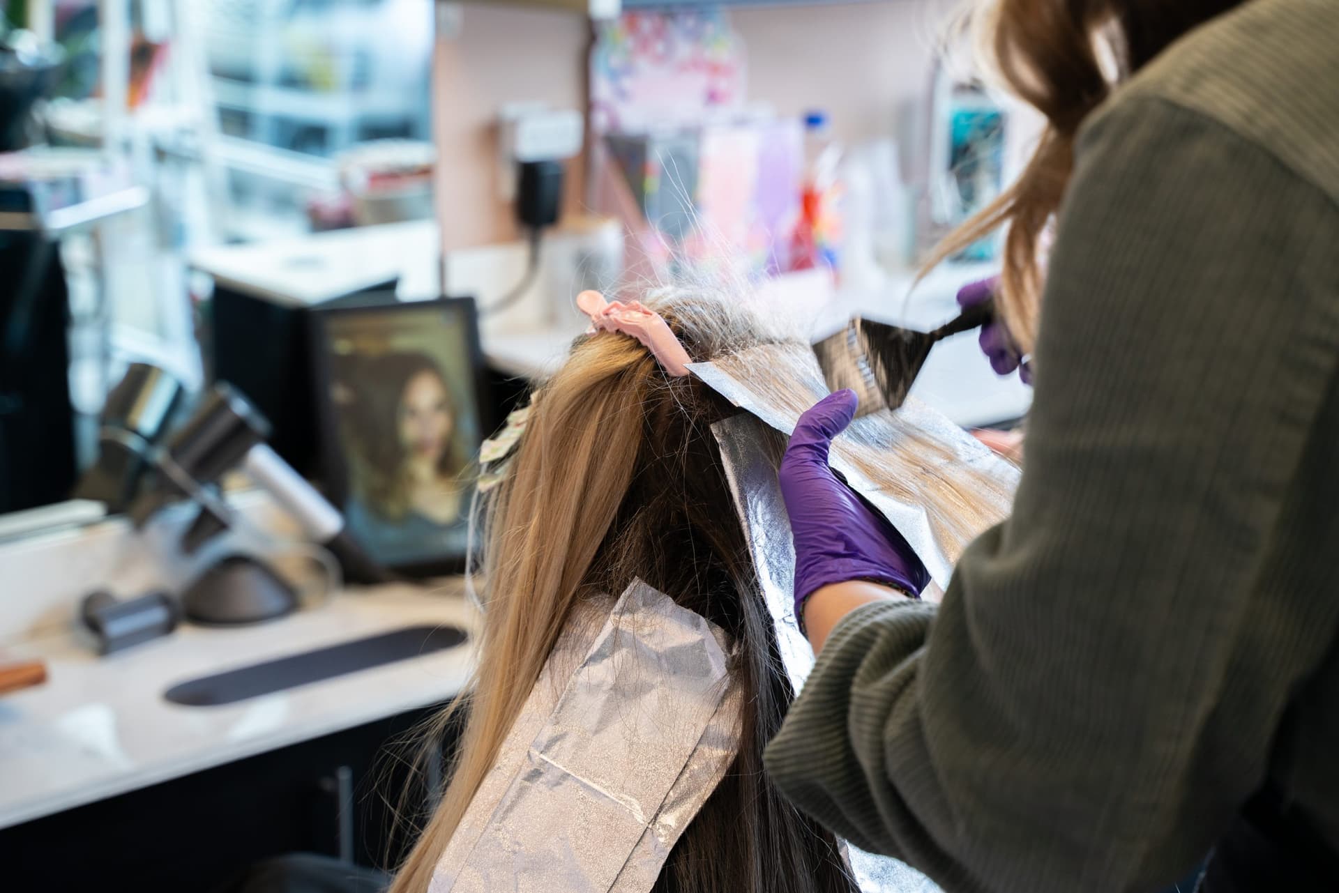Stylist applying highlights to a client's hair in a salon suite